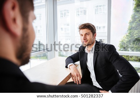 Stok fotoğraf: Smiling Businessman Sitting At His Workplace And Looking Away Isolated On White Background