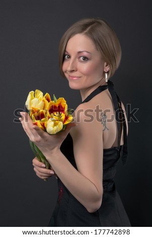 Foto d'archivio: Young Cute Girl With Tattoo On Her Shoulders And A Bouquet Of Coral Roses On A Blue Background Post