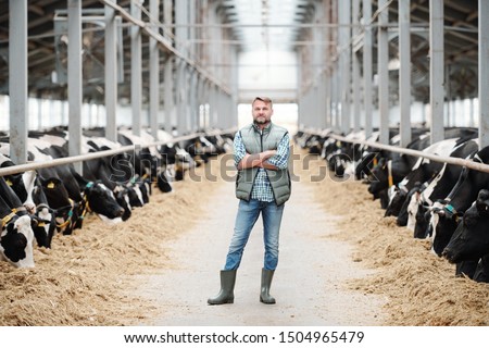 Stockfoto: Confident Cross Armed Staff Of Farmhouse In Workwear Standing In Long Aisle