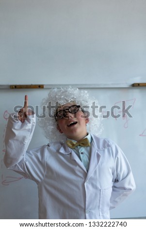 Stok fotoğraf: Front View Of A Caucasian Schoolboy In White Wig Raising Hand While Standing In Front Of The White B