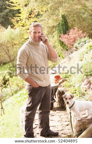 Stock photo: Man Outdoors On Mobile Phone With Dog Whilst On Break From Garde