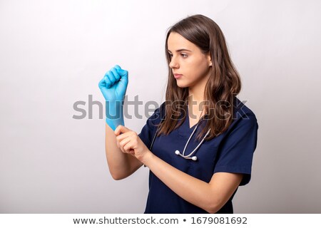Stockfoto: Young Assistant In Uniform Helping Surgeon Put On Medical Gloves