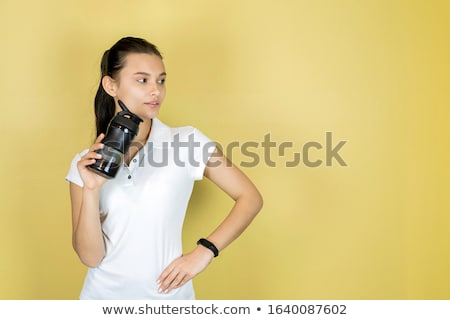 Stockfoto: Young Women In Yellow Sport Shirt Are Drinking Water At The Gym