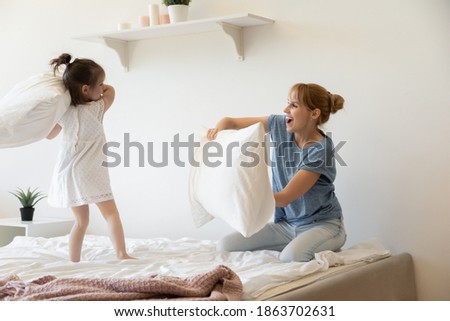 [[stock_photo]]: Two Beautiful Women Jumping From Joy On Bed And Fighting With Pi