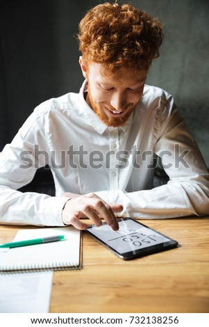 Stockfoto: Young Happy Readhead Bearded Man Using Tablet Looking At Screen