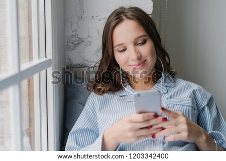 Zdjęcia stock: Photo Of Cauasian Woman Selects Favourite Song In Playlist Uses Contemporary Cellular And High Qual