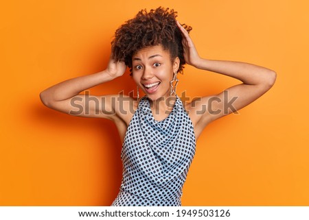 Stock fotó: Brunette Lovely Woman With Toothy Smile Keeps Hand On Head Looks Aside Has Makeup Dressed In Blu