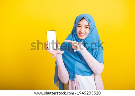 Stock foto: Young Asian Islam Woman Is Smiling Pointing On Smartphone Standi