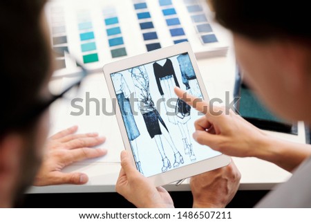 One Of Young Fashion Designers Pointing At Tablet Display During Discussion Foto stock © Pressmaster