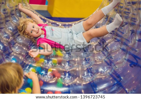 Stock photo: Cute Little Boy And Girl Playing In Zorb A Rolling Plastic Cylinder Ring With A Hole In The Middle