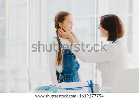 Stockfoto: Photo Of Female Pediatrician Examines Childs Throat Being Professional Skilled Pediatrician Consul