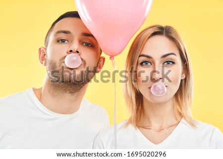 Zdjęcia stock: Young Couple Blowing Bubble With Chewing Gum And Holding Pink Air Balloon