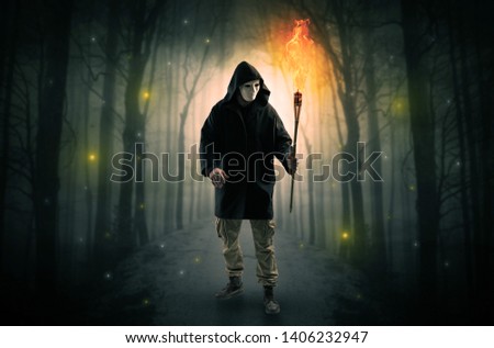 Stockfoto: Man Coming From Dark Forest With Burning Flambeau In His Hand Concept