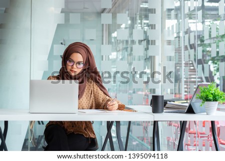 Stock foto: Young Asian Islam Woman Is Sitting Working On Laptop With Serious Looking On The Camera Isolated Whi