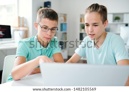 Two Schoolboys Discussing Online Data On Laptop Display At Lesson Foto stock © Pressmaster