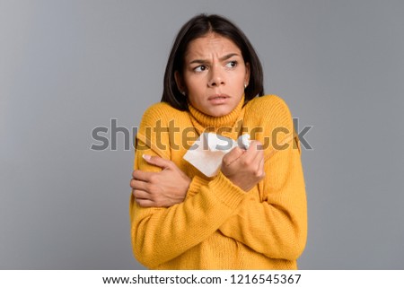 Stockfoto: Frozen Woman Standing Isolated Over Grey Wall Background Holding Napkin