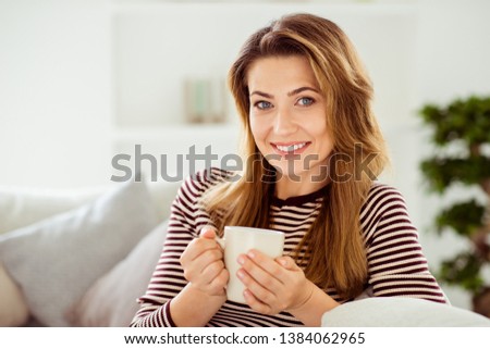 Stock photo: Cheerful Young Women Sitting On A Sofa Holding Cups In A Living Room