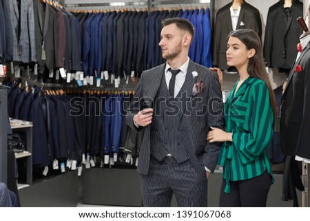 Foto d'archivio: Young Female Shop Assistant Consulting Elegant Male Client Of Boutique