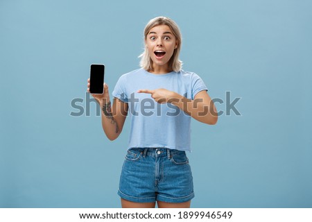 ストックフォト: Charming Smiling Young Blonde Girl In Blue Clothes Showing Funny Gesture On Gray Background