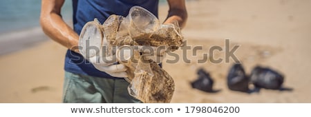 Сток-фото: Man In Gloves Pick Up Plastic Bags That Pollute Sea Problem Of Spilled Rubbish Trash Garbage On The