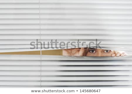 Foto stock: Woman Peeking Through Venetian Blinds