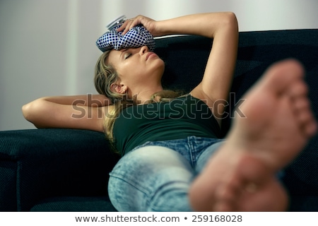 Stock fotó: Woman With Headache Sitting On Sofa With Ice Bag On Head