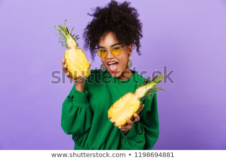 Foto d'archivio: Emotional Excited Young Pretty African Woman Isolated Over Violet Background Holding Pineapple