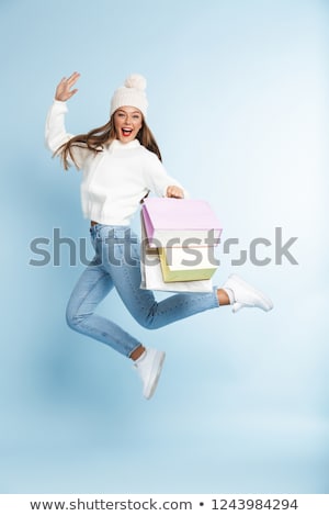 Stok fotoğraf: Cute Young Woman Wearing Winter Hat Isolated Over Blue Wall Background Holding Holding Shopping Bags
