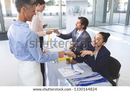 Stockfoto: Side View Of Diverse Business People Checking In At Conference Registration Table While Mixed Race B