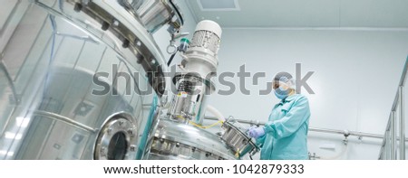 Foto stock: Pharmaceutical Factory Woman Worker In Protective Clothing Operating Production Line In Sterile Envi