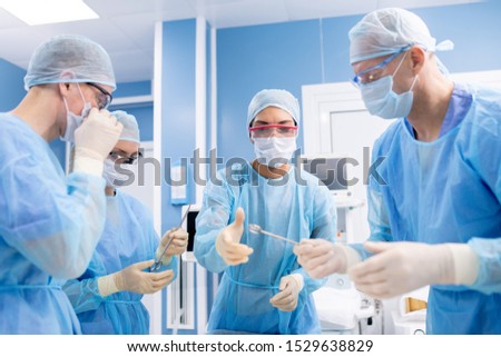 Zdjęcia stock: Group Of Four Professionals In Protective Uniform Taking Surgical Instruments