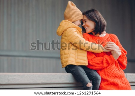 Stock photo: Shot Of Affectionate Young Woman In Warm Red Sweater Looks With Toothy Smile And Love At Her Small