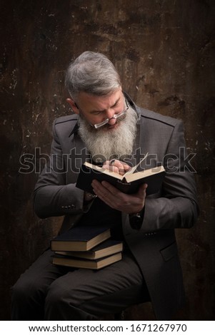 Stockfoto: Mature Man In Elegant Suit Reading A Book In A Luxurious Apartme