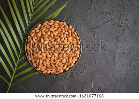 Stockfoto: Composition Of Whole Almond Nuts In Black Plate Placed On Black Stone Table