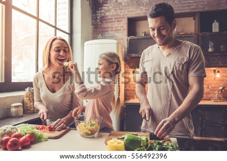 Stockfoto: Little Girl With Her Mother In The Kitchen Eating A Fresh Fruit