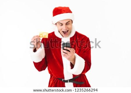 ストックフォト: Image Of Delighted Man 30s In Santa Claus Costume Holding Smartp