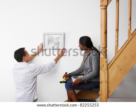 Stok fotoğraf: Woman Helping Man To Hang Picture