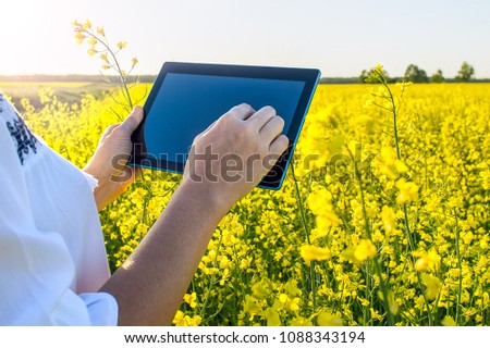 Foto d'archivio: Female Farmer With Digital Tablet In Oilseed Rapeseed Cultivated