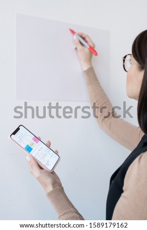 Stock foto: Young Business Coach Holding Smartphone With Flow Chart Before Presentation