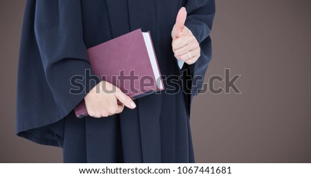 Foto stock: Female Judge Mid Section With Book And Thumbs Up Against Grey Wall