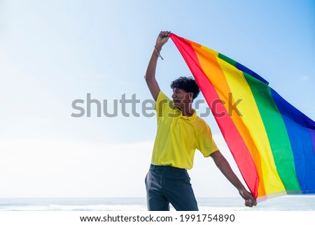 Stock photo: Man With A Rainbow Flag In Front Of The Ocean