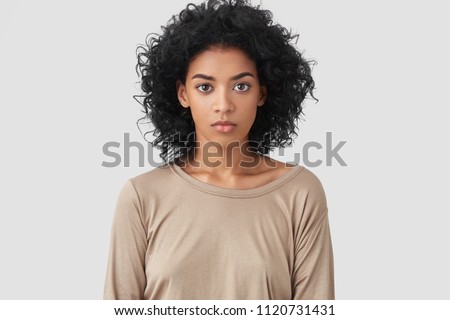 Stock photo: Photo Of Serious Curly Haired Woman Looks Confidently At Camera Wears Formal Neat Clothes Keeps Bo