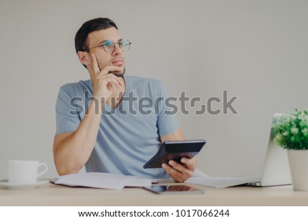 Stockfoto: Pensive Male Manager In Round Spectacles Thinks About Creating Interesting Project Involved In Pape