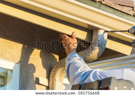 Stock photo: Worker Attaching Aluminum Rain Gutter And Down Spout To Fascia O