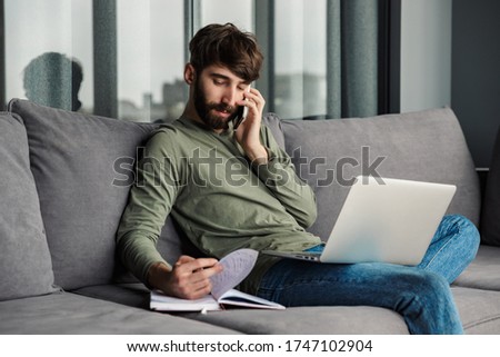 Stockfoto: Image Of Man Talking On Smartphone And Reading Diary While Sitting