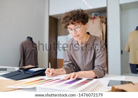 Imagine de stoc: Young Businesswoman Looking Through Collectioln Of Textile Samples