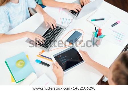 Stockfoto: Hands Of Three Clever School Learners With Modern Mobile Gadgets Over Desk