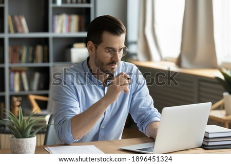 [[stock_photo]]: Young Pensive Businessman Reading Online Information On Laptop Display