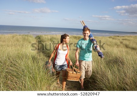 Stock photo: Young Couple Carrying Picnic Basket And Windbreak Walking Throug