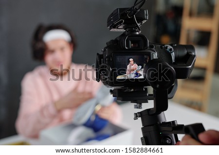 [[stock_photo]]: Young Vlogger In Casualwear Showing Sneakers On Display Of Digital Video Camera